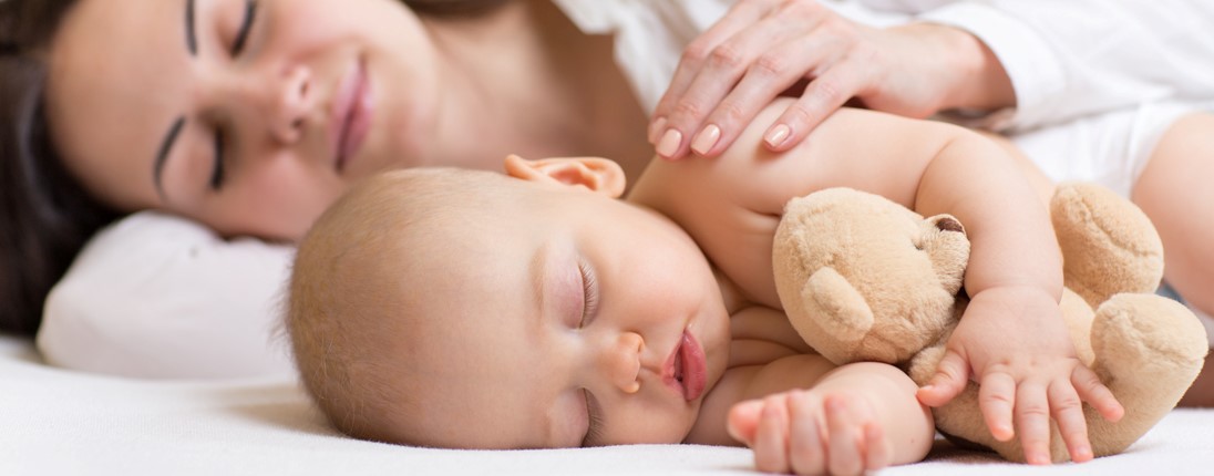 Une mère fait la sieste à côté de son bébé endormi