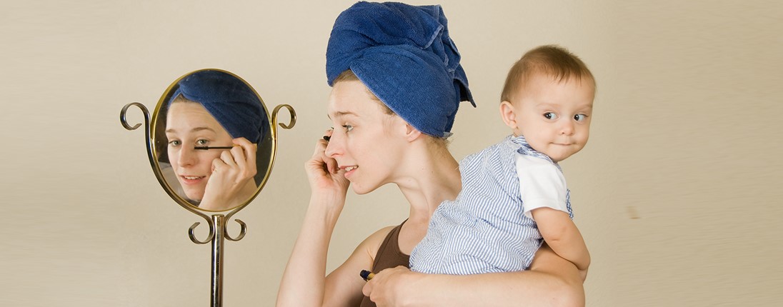 Une femme se maquille avec un bébé dans les bras