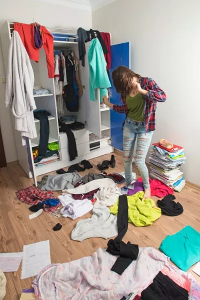 Une adolescente danse dans une chambre en désordre.