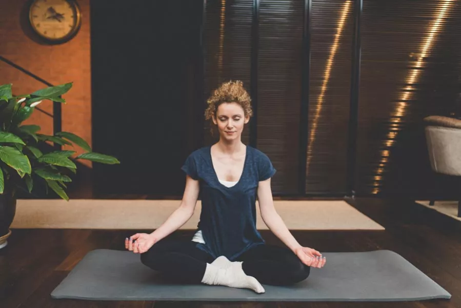 Une femme pratique le yoga dans son salon