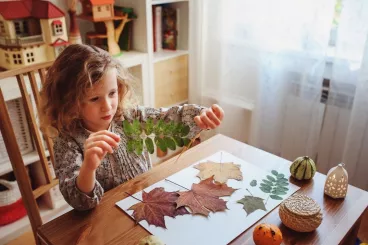 Les feuilles d'automne se ramassent... en famille ! Une petite fille réaliser un herbier