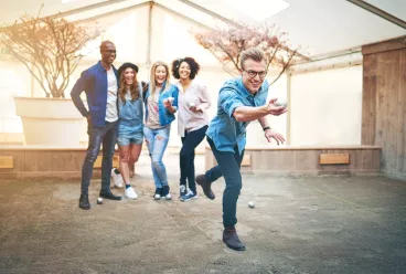 Trois femmes et deux hommes qui rient et jouent à la pétanque