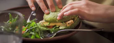 Une personne mangeant un hamburger végatal