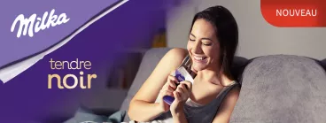Une femme déguste Milka Noir sur son canapé