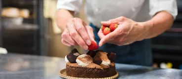 Un chef patissier élabore un gâteau au chocolat et aux fraises