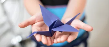 Un enfant tient un oiseau en origami dans ses mains