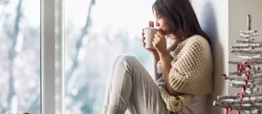 Une femme confortablement assise près d’une fenêtre 