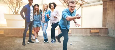 Trois femmes et deux hommes qui rient et jouent à la pétanque