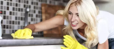 Une femme nettoye sa cuisine avec un produit d’entretien.