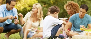 Idées gastronomiques pour un pique-nique 100% pratique Un groupe de gens partagent un pique-nique dans un parc.