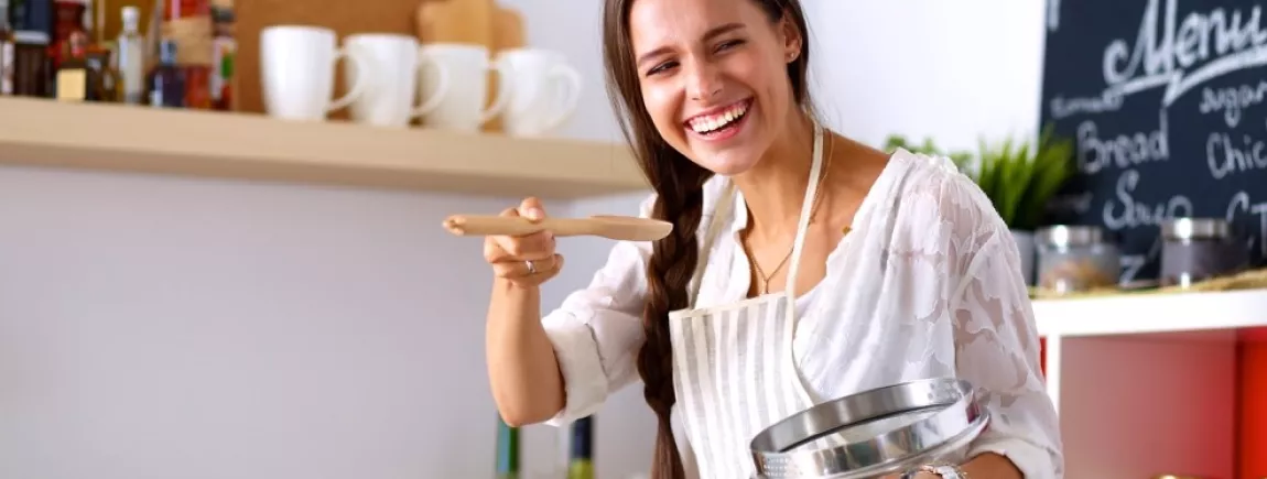 Une femme fait la cuisine en souriant