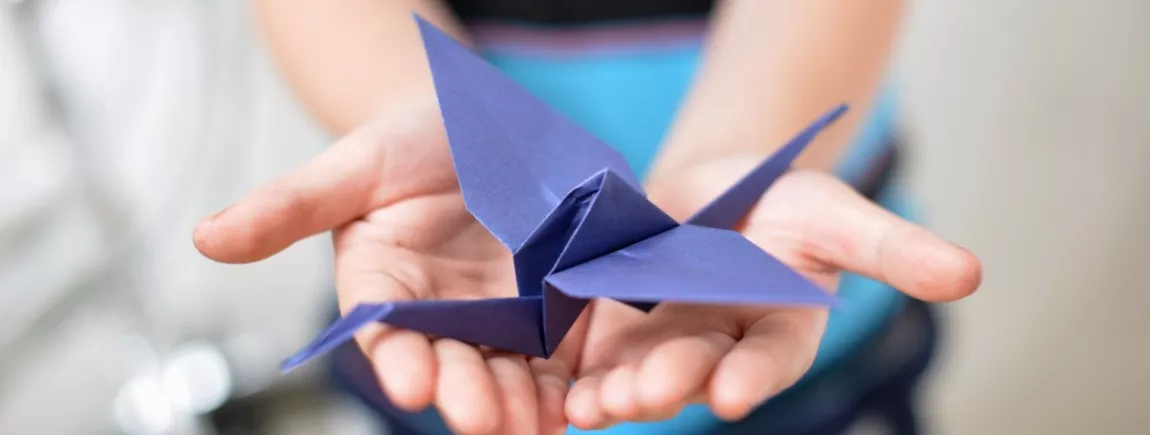 Des vacances en mode travaux manuels ! Un enfant tient un oiseau en origami dans ses mains