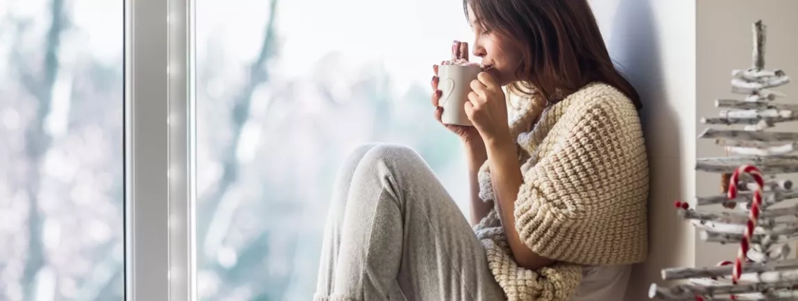 Une femme confortablement assise près d’une fenêtre 