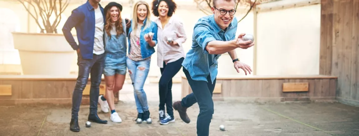 Trois femmes et deux hommes qui rient et jouent à la pétanque