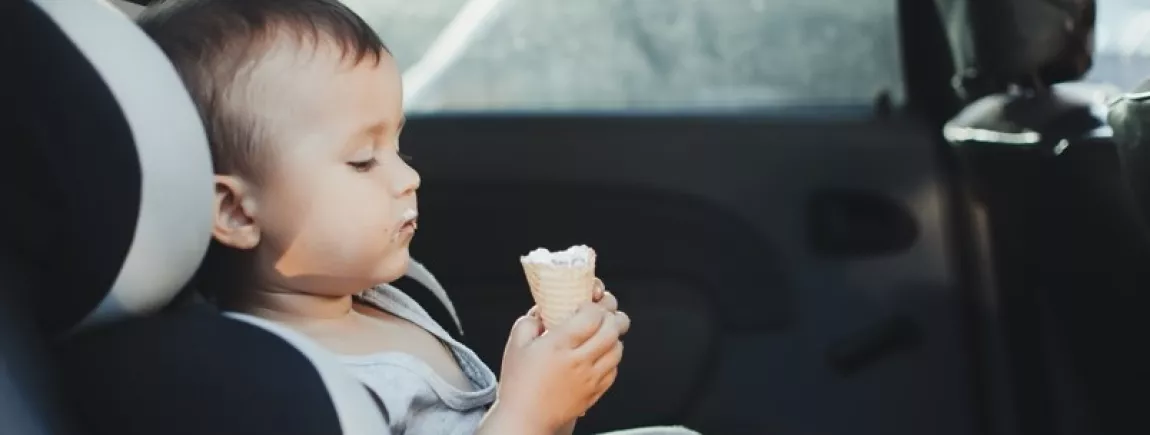 Chassé-croisé des vacances : et si on mangeait dans la voiture ? Un enfant qui mange une glace dans une voiture