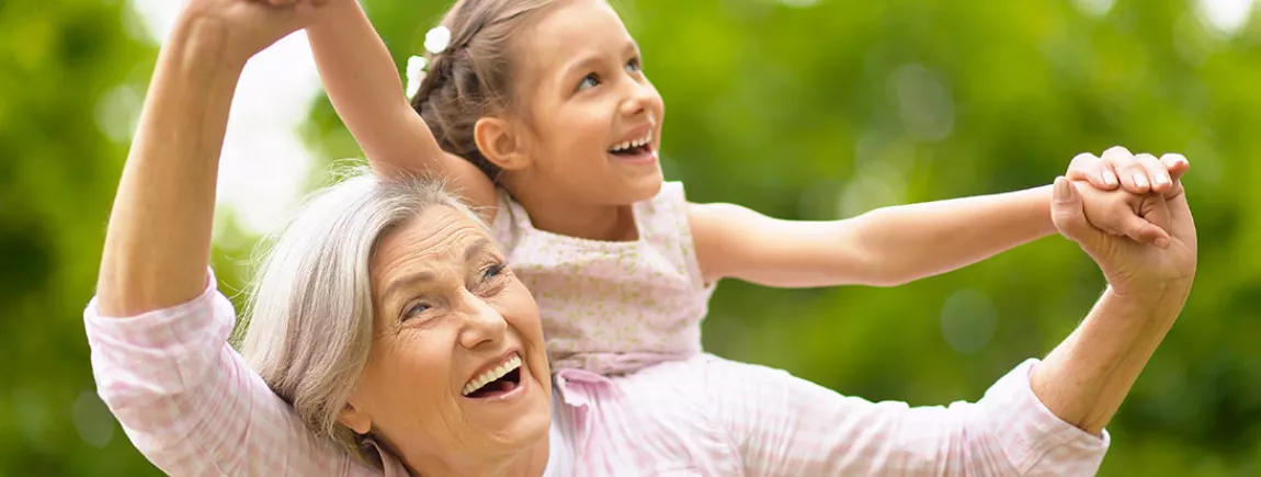 5 preuves que passer du temps avec sa grand-mère est essentiel Une grand-mère et sa petite fille sur son dos qui passent un bon moment dans un espace extérieur