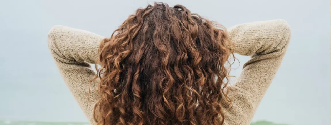 Je veux des beaux cheveux (même en automne) ! Une femme se passe la main dans les cheveux